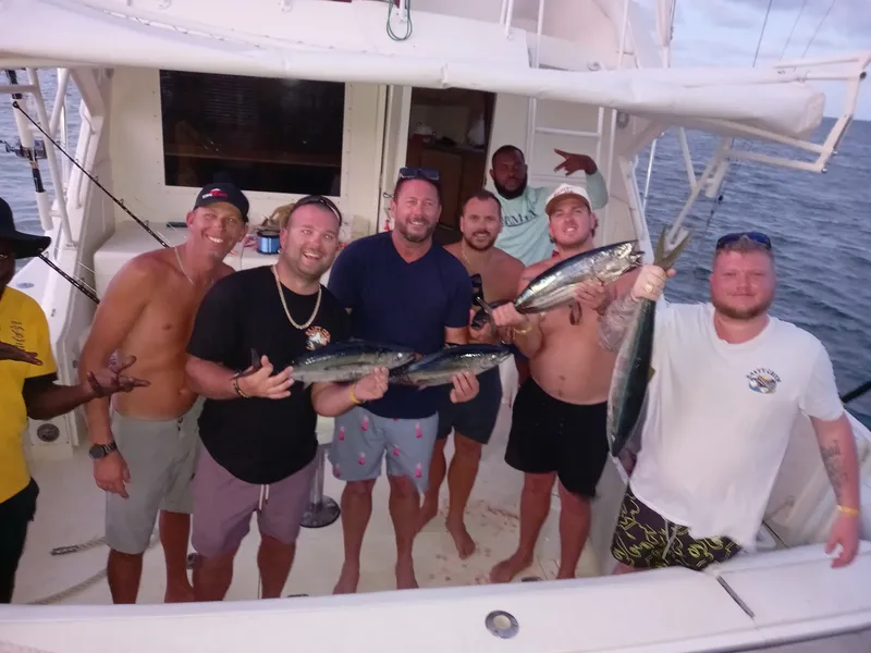 Group of friends celebrating tuna catches aboard Vodka Shot at sunset